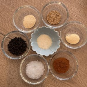 Zutaten für klassischen BBQ Rub – Gewürze wie Pfeffer, Salz, Paprika und Senfkörner für den Mörser