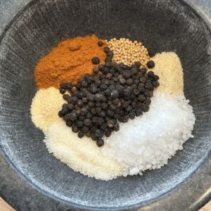 Gewürze im Granitmörser für BBQ Rub – Pfeffer, Salz und Paprika vor dem Zerkleinern
