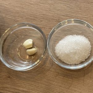 Zutaten für Knoblauchsalz – frische Knoblauchzehen und grobes Salz für den Mörser