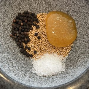 Honig Senf Rub im Mörser – Senfkörner, Pfeffer, Salz und Honig werden für BBQ Gewürzmischung zusammengegeben
