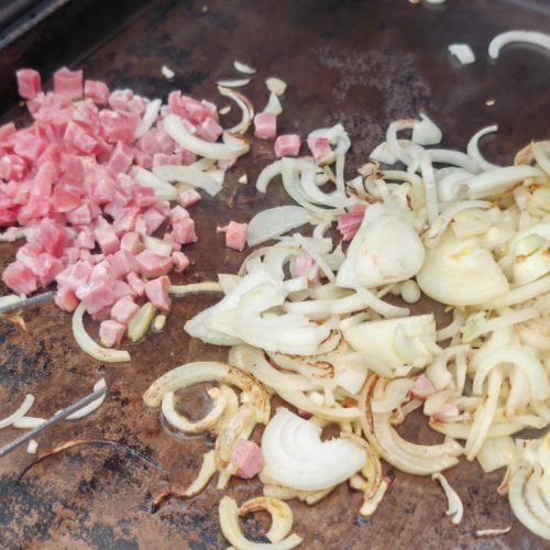 Zwiebeln und Schinkenwürfel rösten auf einer Plancha oder Grillplatte