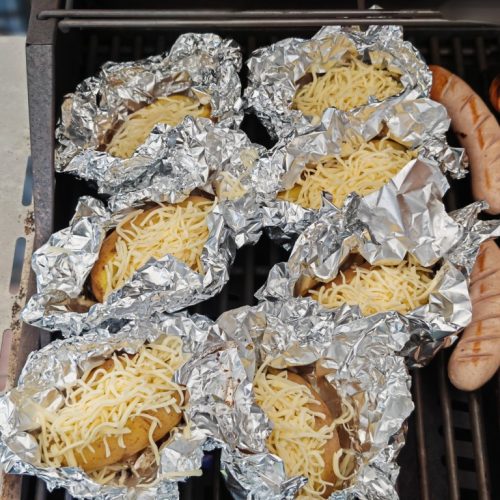 Grillkartoffeln in Alufolie mit reichlich geriebenem Käse auf dem Grill