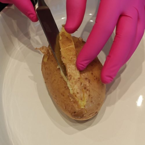 Vorgekochte Kartoffel wird mit einem Messer mittig eingeschnitten