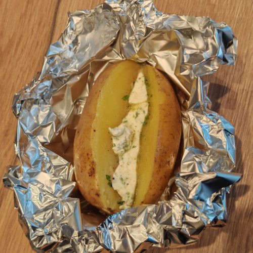Mit Kräuterbutter gefüllte Kartoffel in Alufolie vorbereitet zum Grillen